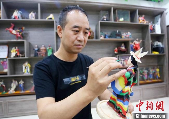 圖為安秋平正在創(chuàng)作代表隴南文縣民俗的《白馬人》作品。　高展 攝