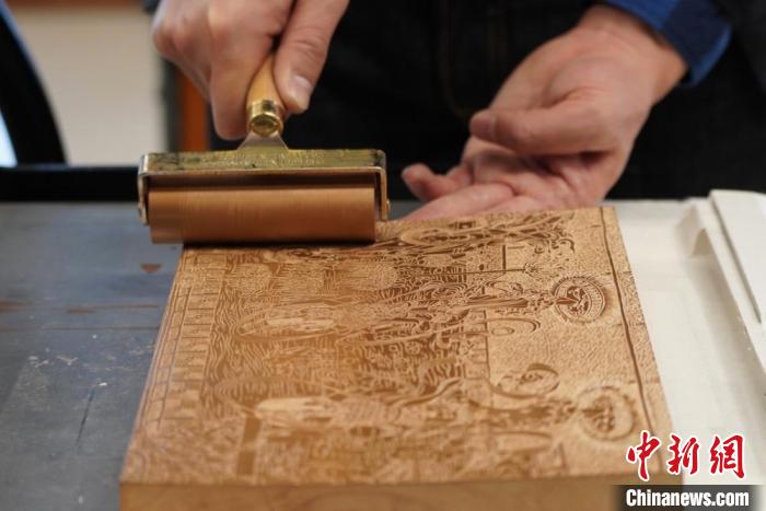 圖為徐晉林工作室工作人員正在給雕好壁畫的版面滾油墨?！【琶赖┰?　攝