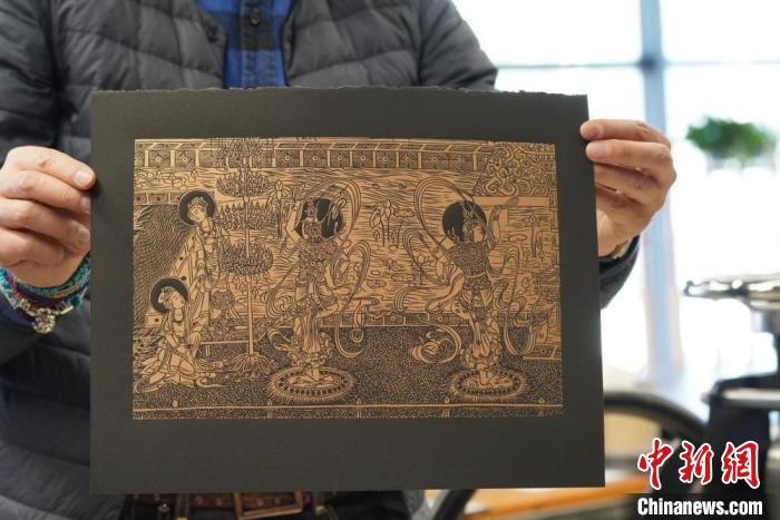 圖為手工書藝人展示敦煌雕版壁畫印刷品。　九美旦增 　攝