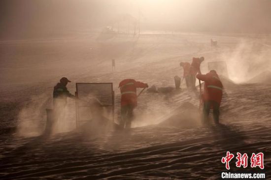 圖為敦煌市鳴沙山月牙泉景區(qū)“駱駝保姆”清理駱駝糞便?！垥粤?攝
