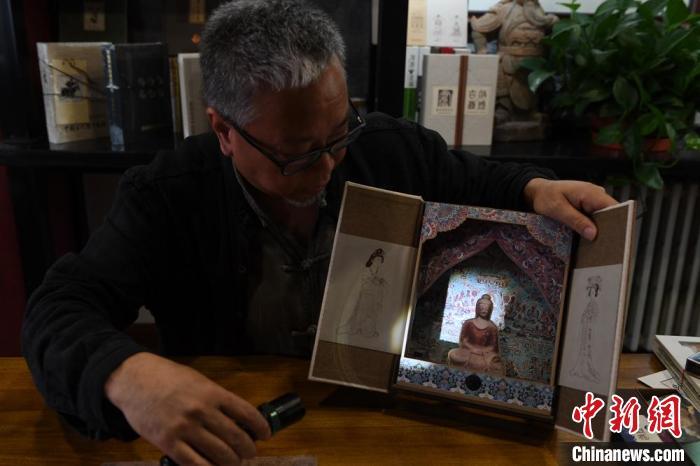 圖為讀者出版集團(tuán)讀者晉林工作室獨(dú)立出品人徐晉林，展示互動(dòng)性強(qiáng)的敦煌題材手工書。(資料圖) 楊艷敏 攝