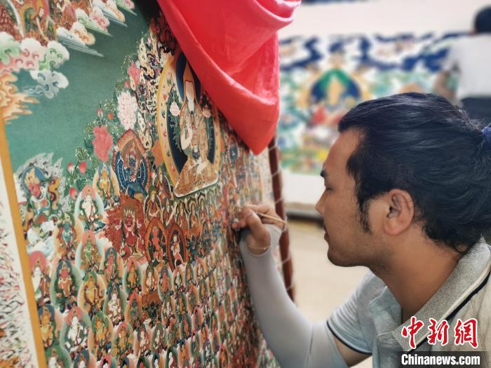 圖為更登才讓的徒弟繪畫唐卡?！?zhí)砀?攝