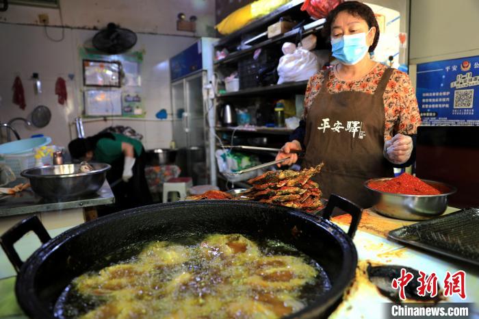 圖為平安驛·河湟民俗文化體驗地內(nèi)的商戶炸干板魚?！⊙Φ?攝